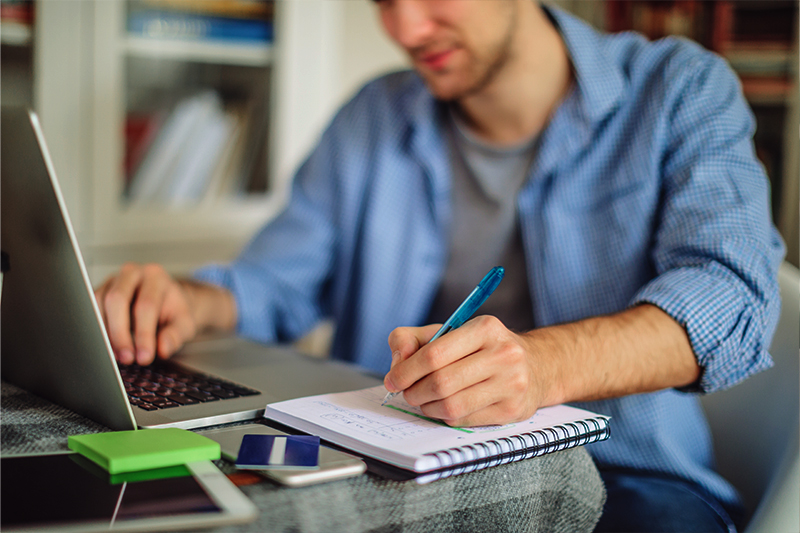 Male real estate student that is using an apple laptop to take a real estate course on the Eagle Learning Institute platform.